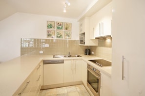 A kitchen with a dishwasher, oven, microwave, and a sink.