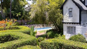 Une maison traditionnelle dotée d’une piscine, entourée de jardins et d’arbres bien entretenus.