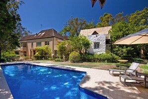 A swimming pool with lounge chairs and a stone building.