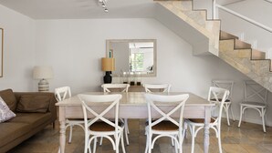 Un espace repas comprenant une table et des chaises, un escalier et un canapé.