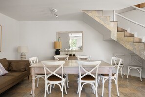 Un comedor con una mesa, sillas, una escalera y un sofá.