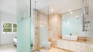 Une salle de bain moderne avec une douche à parois de verre, des toilettes et un meuble-lavabo avec un évier.