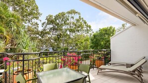 A balcony with a table and chairs, surrounded by potted plants and flowers. - Bayona 2 - Family Beach Charm (Little Cove)