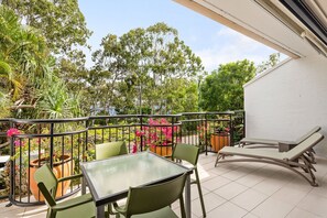 A balcony with a table and chairs, surrounded by potted plants and flowers. - Bayona 2 - Family Beach Charm (Little Cove)