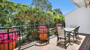 An outdoor patio with a table and chairs, surrounded by a railing and potted plants. - Bayona 4 - Balcony Tranquility (Little Cove)