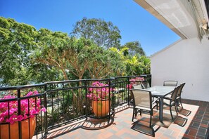 An outdoor patio with a table and chairs, surrounded by a railing and potted plants. - Bayona 4 - Balcony Tranquility (Little Cove)