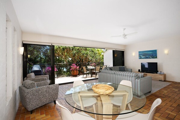 A modern living room with a glass table, sofas, and a TV.