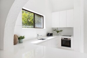 Eine moderne Küche mit weißen Schränken, einem eingebauten Backofen und einem Fenster mit Blick auf Grünflächen.