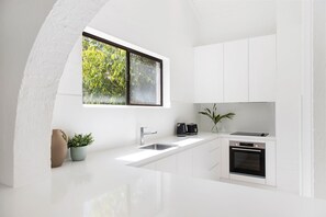 Enjoy a kitchen with a large window offering a view of lush greenery, oven, and coffee maker.