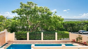 A swimming pool with a clear blue water surface, surrounded by a low beige wall and a metal fence. - Penthouse with Incredible Views & Pool (Noosa Heads)