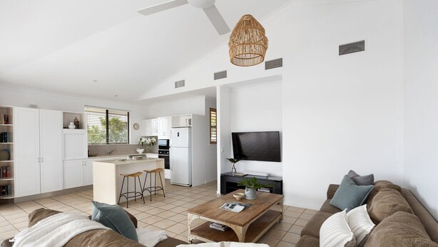 A modern living space with a kitchen, dining area, and a seating area with a sofa and coffee table. - Penthouse with Incredible Views & Pool (Noosa Heads)
