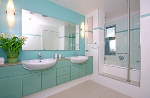 A bathroom with two sinks, a large mirror, and a shower.