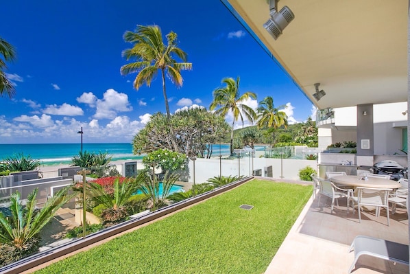 A modern outdoor patio with a pool, dining area, and a view of the ocean.