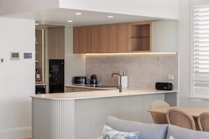 Una cucina moderna con elettrodomestici integrati, un'isola a incasso e un'area pranzo con tavolo e sedie.