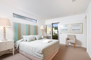 A bedroom with a bed, bedside tables, a chair, and a window.