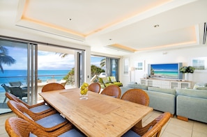 Relax in this spacious living area with a large dining table, comfortable sofa, and flat-screen TV, plus a balcony with ocean views.