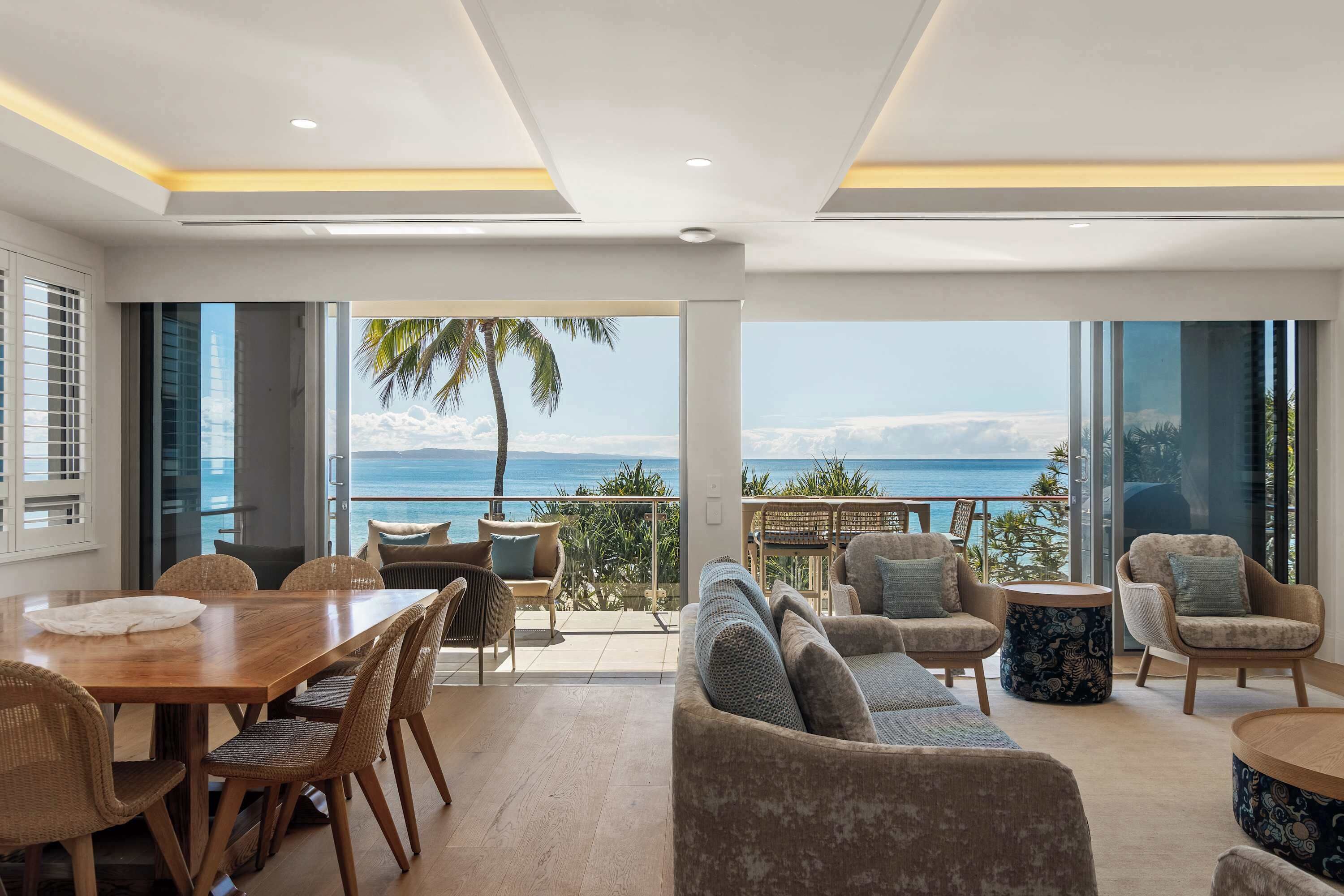 A spacious living area with a large window overlooking a balcony with a view of the ocean.