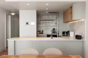 Een moderne keuken met een centraal eiland, een ingebouwde wijnkast en moderne apparatuur.