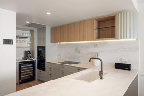 A modern kitchen with a built-in oven, a coffee machine, and a wine rack.