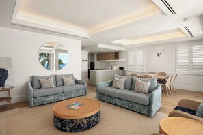 A modern living room with two sofas, a coffee table, and a dining area with a table and chairs.