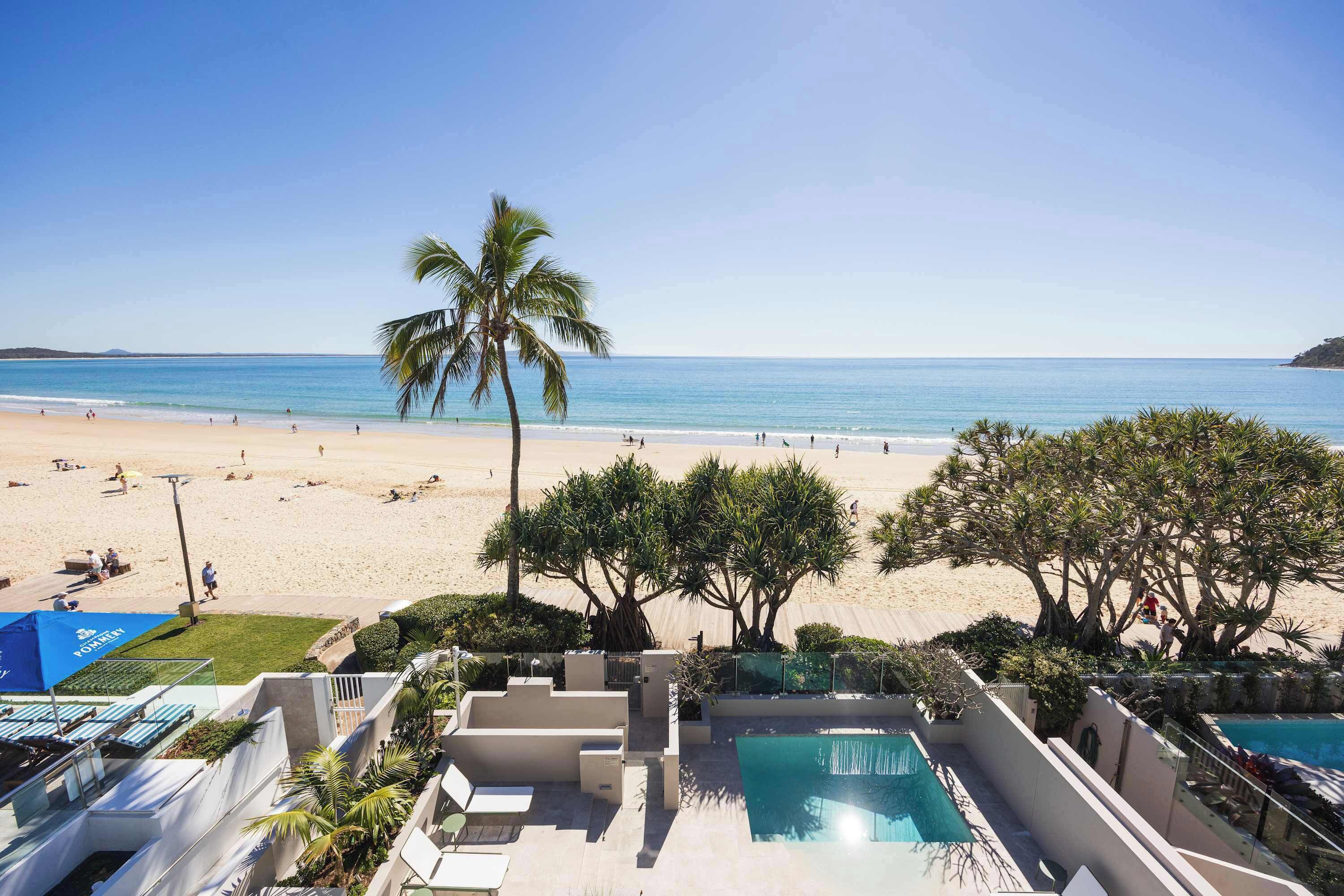 A pool area with a view of the beach and ocean.