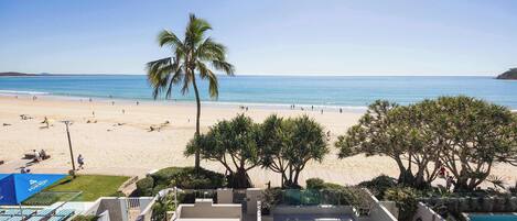 A pool area with a view of the beach and ocean.