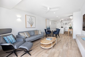 Un salon moderne avec un canapé gris, une table basse et un coin repas comprenant des chaises et une table.