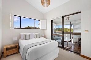 Relax in this serene bedroom with a large bed, nightstand, and stunning views of the lush landscape.