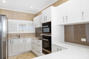 Enjoy cooking in this well-lit kitchen with a stainless steel refrigerator, oven, and sleek cabinetry.