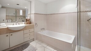 Un baño moderno con un lavamanos grande, una bañera y un box de ducha de vidrio.