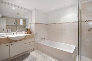 A modern bathroom with a large sink, a bathtub, and a glass shower enclosure.