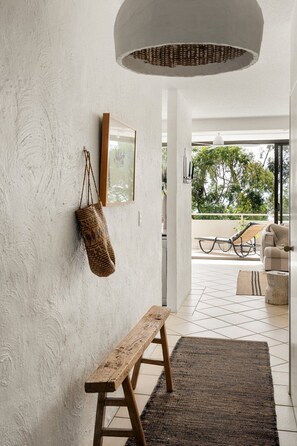Un interno moderno con una panca, un cesto intrecciato e un quadro appeso al muro.