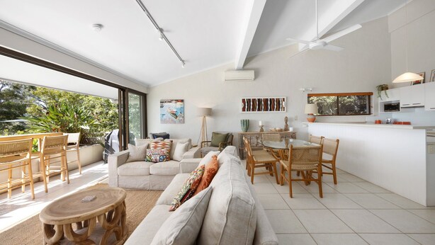 A modern living space with a large sofa, dining area, and kitchen. - Cove Point 5 - Stylish Cove Escape (Noosa Heads)
