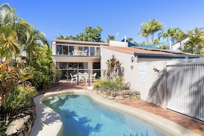 Ein Wohnhaus mit Swimmingpool, überdachter Terrasse und einem umzäunten Garten.