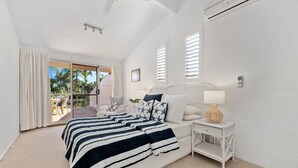 Une chambre avec un grand lit, une table de chevet, une lampe et une vue sur l’extérieur.