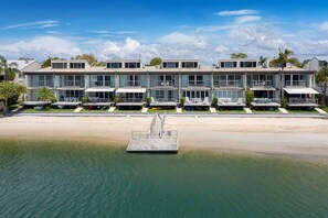 A beachfront hotel with multiple balconies, a sandy beach, and a clear sky.