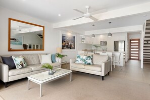 A modern living room with a sofa, coffee table, and a dining area with chairs.