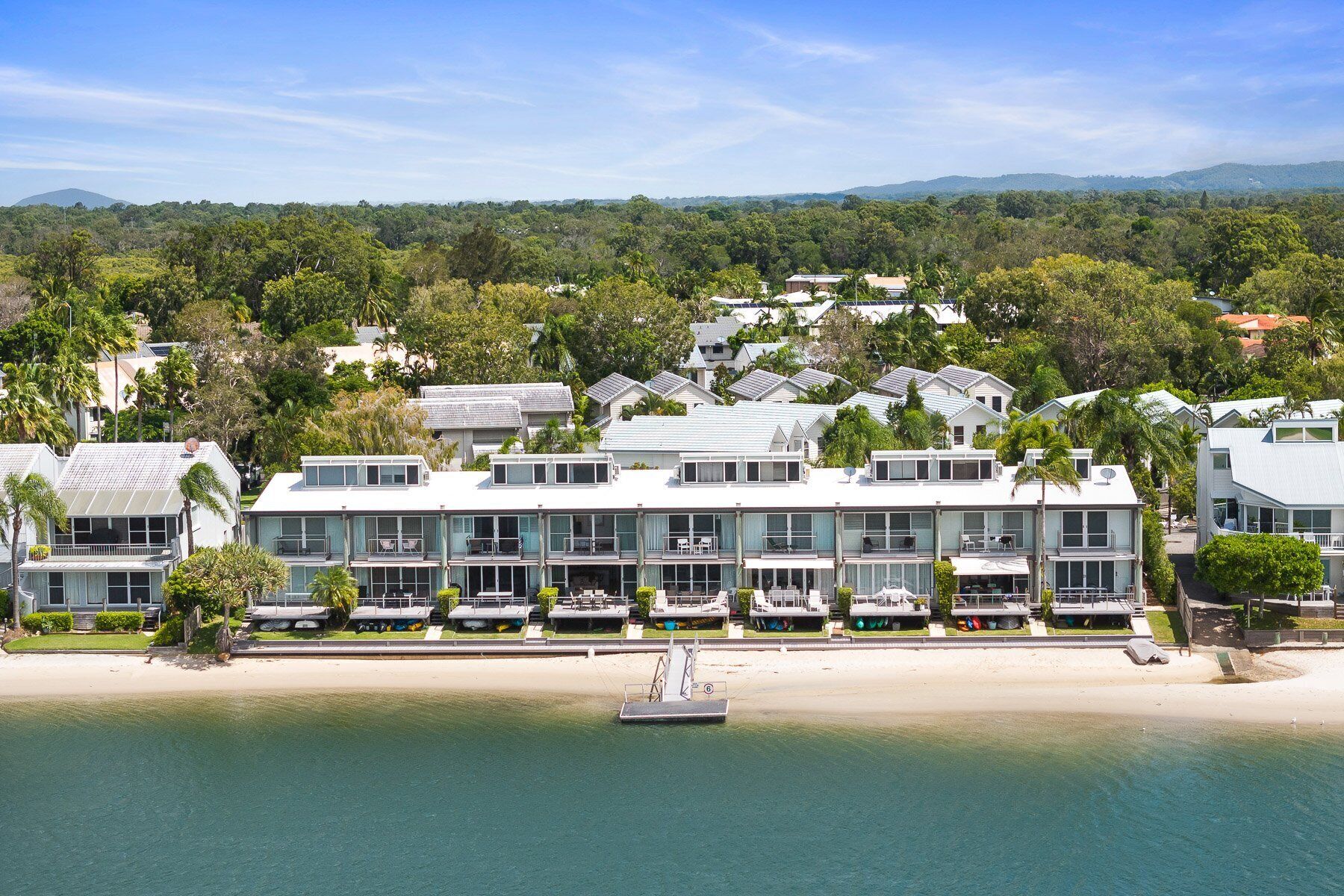 A beachfront hotel with multiple-story buildings, a sandy beach, and a clear view of the ocean.