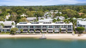 A beachfront hotel with multiple-story buildings, a sandy beach, and a clear view of the ocean.