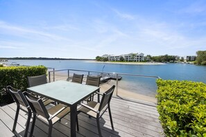 Una terrazza con tavolo e sedie affacciata su un lago, con edifici sullo sfondo.