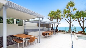 An outdoor patio with a dining area, a pool, and a view of the sea.