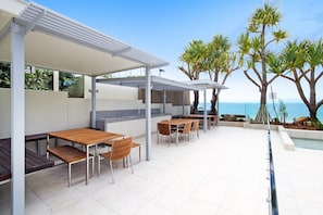 An outdoor patio with a dining area, a pool, and a view of the sea. - Fairshore 15 - Noosa Main Beach Stay (Noosa Heads)