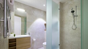 A modern bathroom with a glass shower enclosure, a wooden vanity, and a toilet.