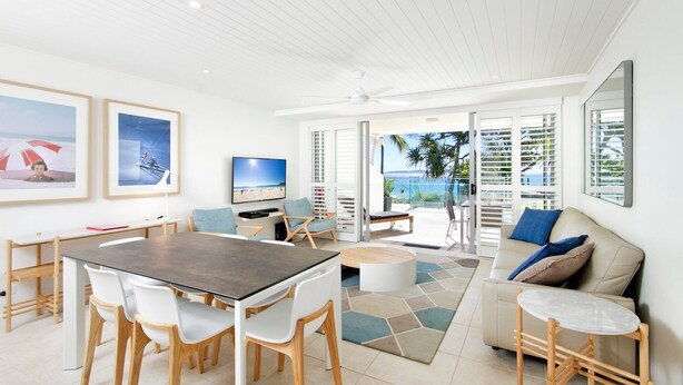 A modern living room with a dining area, a sofa, and a TV.