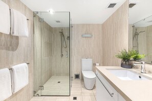 Une salle de bain moderne avec une douche à parois de verre, des toilettes, un lavabo et un miroir.