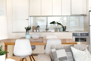 A modern kitchen with a dining area, large windows, and a built-in oven.