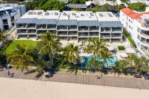 A hotel with multiple balconies, a swimming pool, and palm trees.
