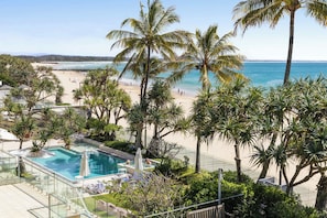 A resort with a pool, beach, and palm trees.