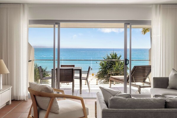 A balcony with a view of the sea, furnished with a sofa and chairs.