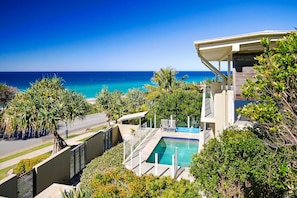 A pool area with a view of the ocean, surrounded by tropical vegetation.